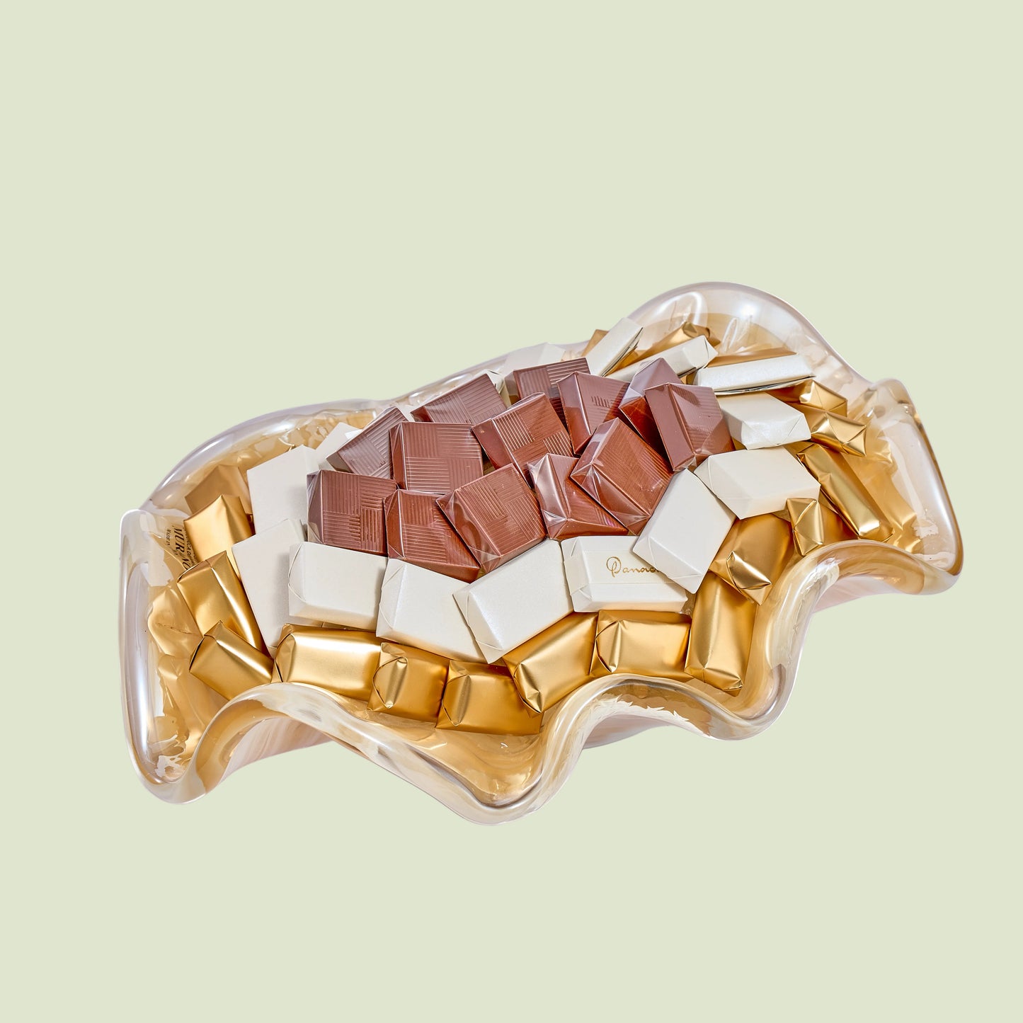 Clear Murano crystal wavy bowl with assorted wrapped chocolates in circular arrangement