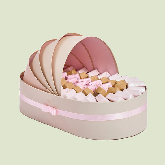 Pink and white dragées in baby girl shell cradle gift arrangement side view