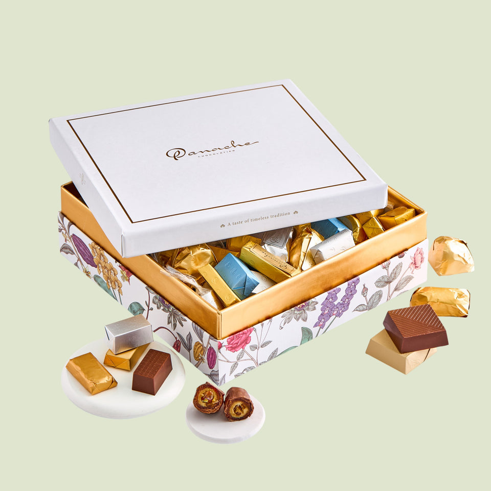 Open floral-patterned chocolate box with assorted chocolates on a light green background