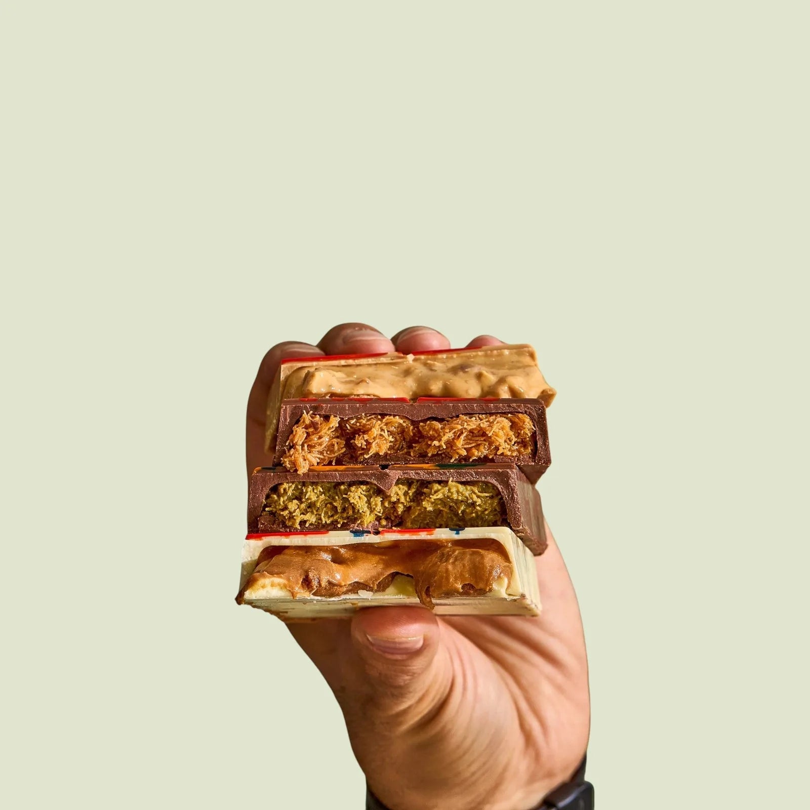Panache signature chocolate bars, held in hand to reveal their layered fillings